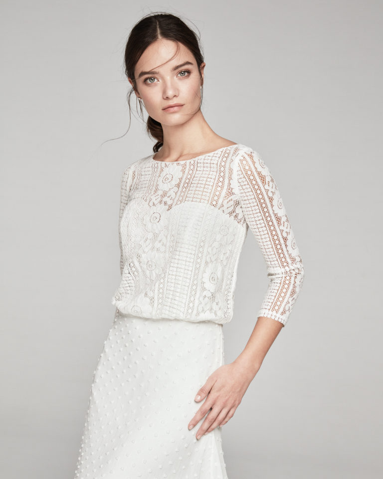 Vestido de novia estilo boho de encaje. Escote barco, manga 3/4 y falda en bambula de topos. Disponible en color natural. Colección ALMANOVIA 2019.