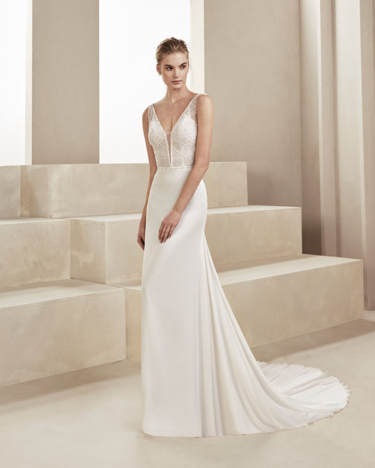Sheath-style wedding dress in beaded chiffon. With deep-plunge neckline and V-back. Available in natural. 2019 ALMA_NOVIA Collection.