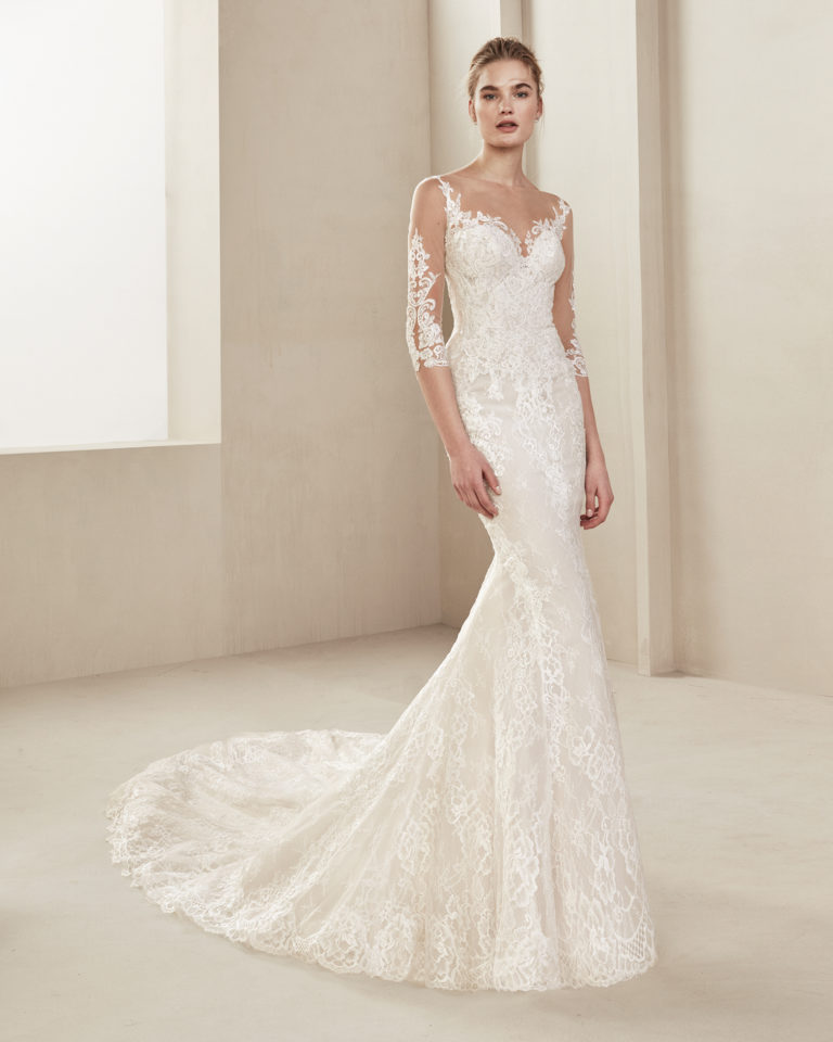 Mermaid-style lace wedding dress. With illusion neckline and three-quarter sleeves. Available in natural/nude and natural. 2019 ALMA_NOVIA Collection.