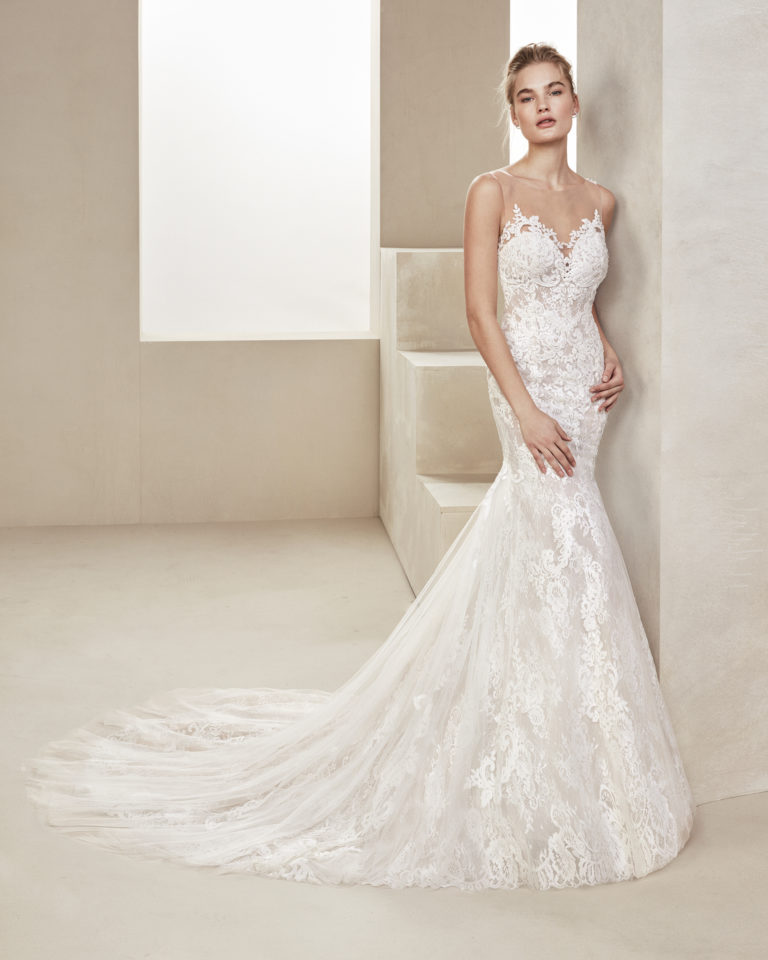 Mermaid-style beaded lace wedding dress. With illusion neckline and back in tulle. Available in natural/nude and natural. 2019 ALMA_NOVIA Collection.