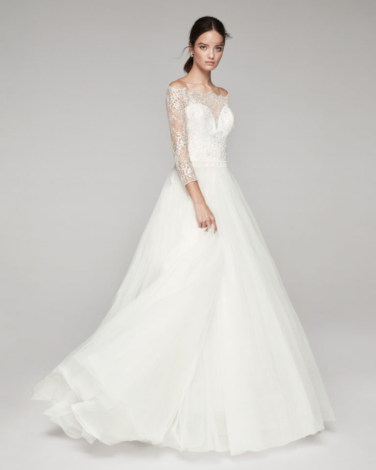 Romantic wedding dress in tulle and beaded lace. With off-the-shoulder neckline. Available in natural. 2019 ALMA_NOVIA Collection.