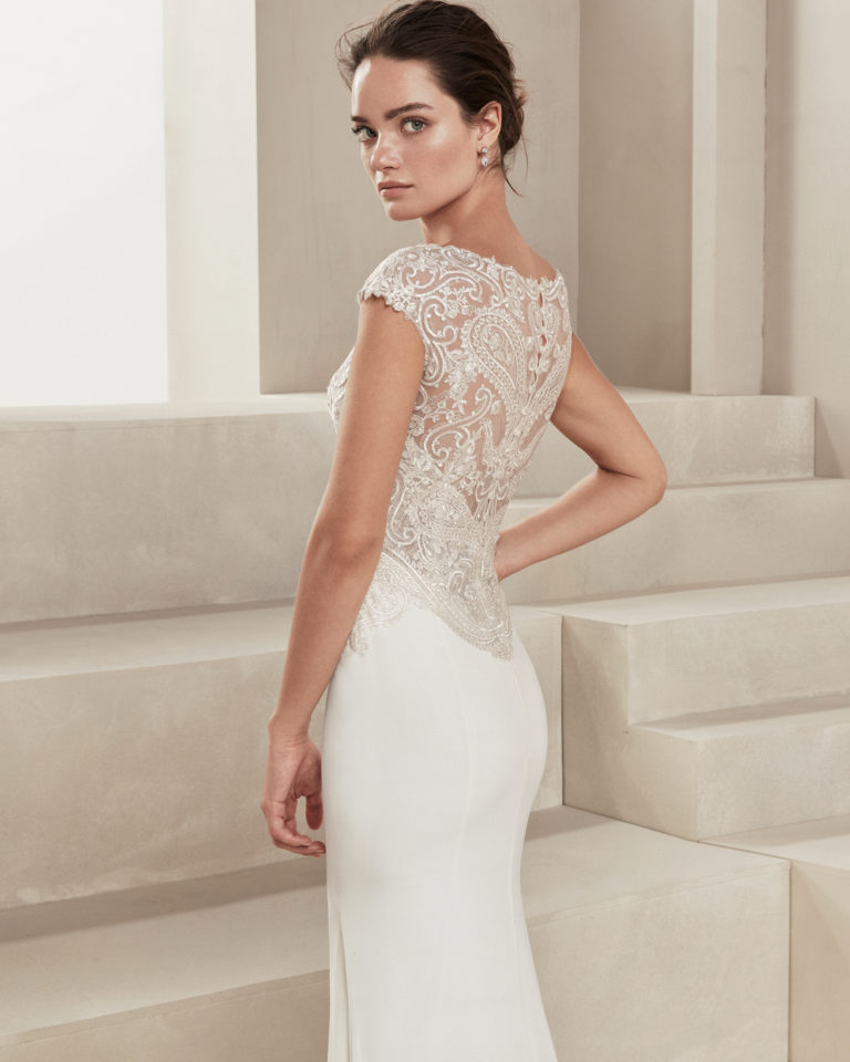 Sheath-style wedding dress in crepe Georgette and beaded lace. With V-neckline. Available in natural. 2019 ALMA_NOVIA Collection.