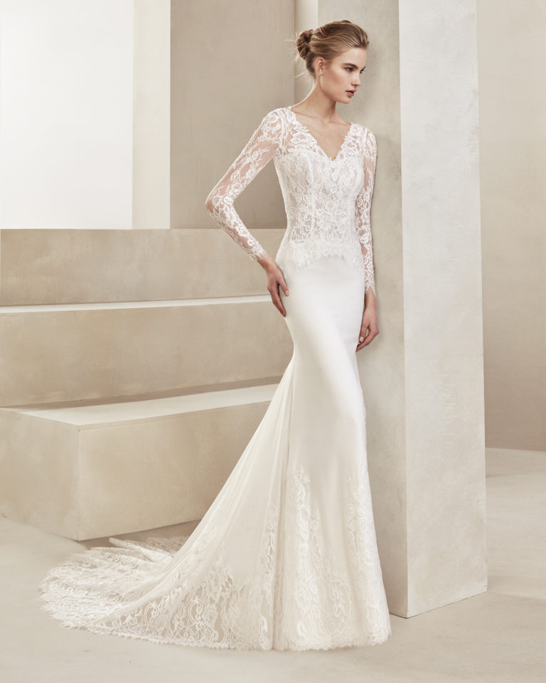 Sheath-style wedding dress in crepe Georgette and beaded lace. With V-neckline and long lace sleeves. Available in natural. 2019 ALMANOVIA Collection.