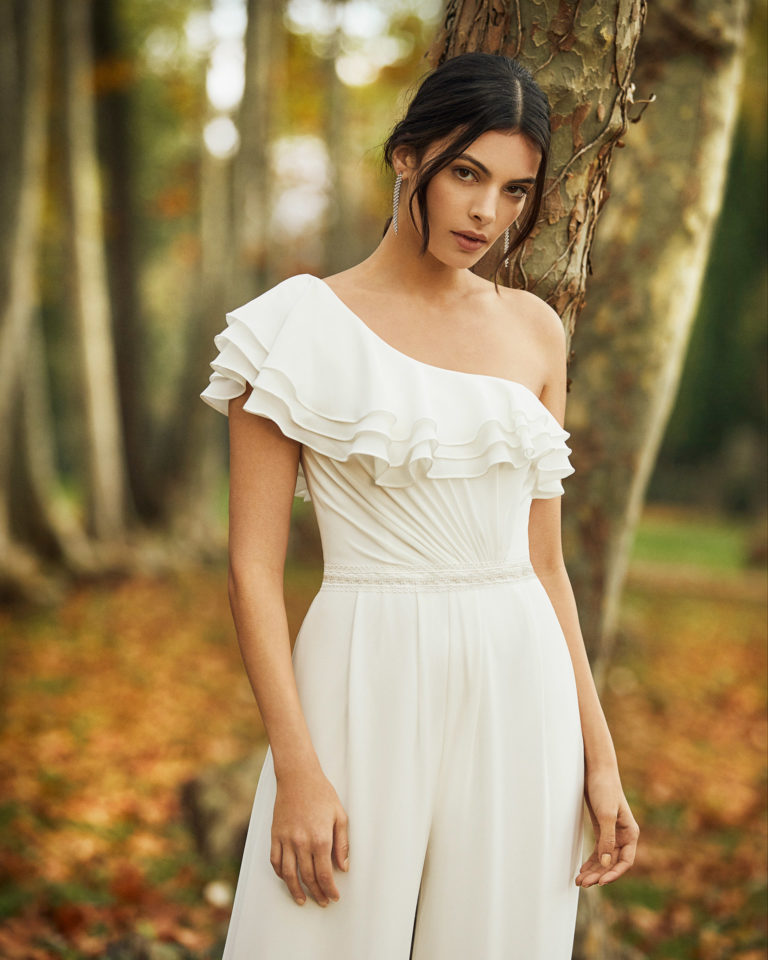 Bridal trouser suit in crepe Georgette with asymmetrical neckline and flounces. 2020 ALMA_NOVIA Collection.
