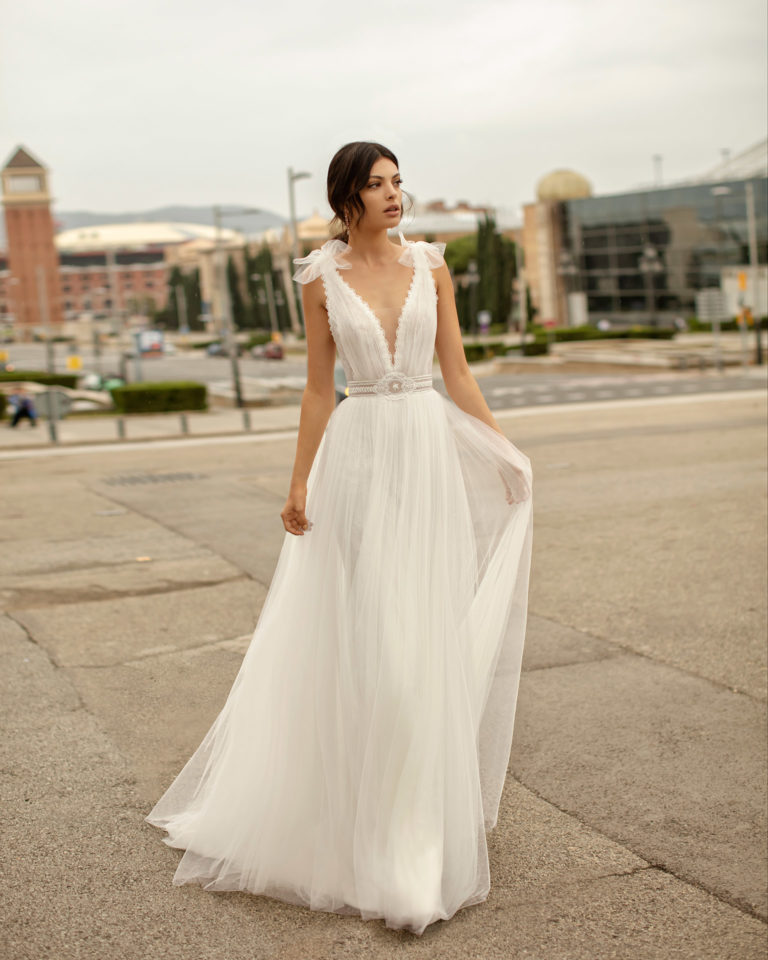 Romantic wedding dress and watteau train in soft tulle and lace with beading, with deep-plunge neckline. 2020 ALMANOVIA Collection.