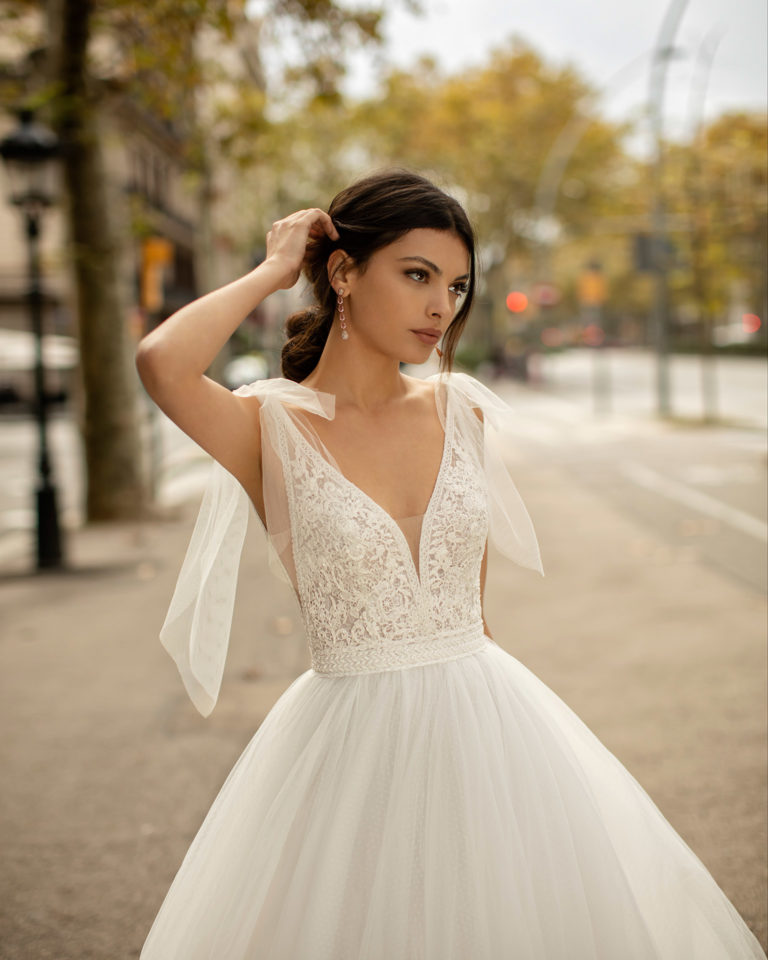 Princess-style lace and tulle wedding dress with beading, deep-plunge neckline and V-back. 2020 ALMA_NOVIA Collection.