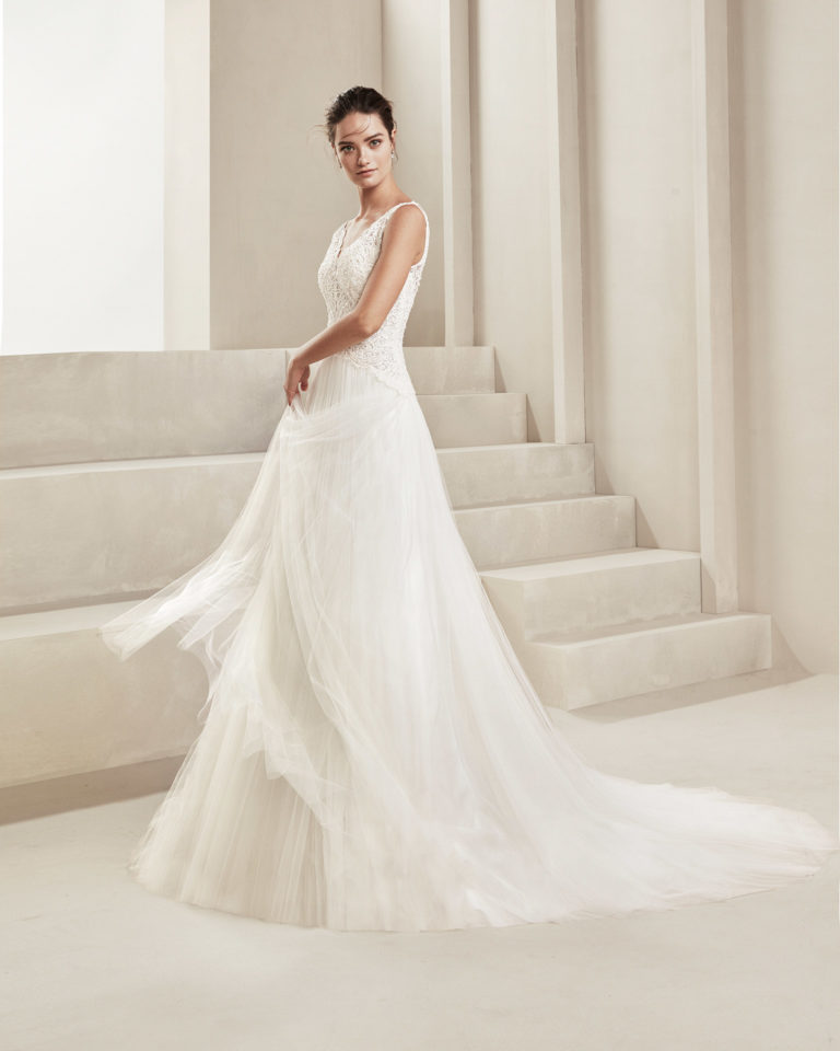 Vestido de novia romántico de tul suave, encaje y pedrería. Con escote V y espalda en tul. Disponible en color natural. Colección ALMANOVIA 2020.
