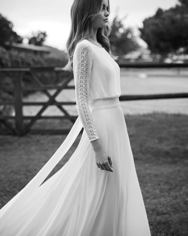 Long bridal dress, two-piece and straight cut. Crafted in georgette with a round neckline, lace sleeves, and open back with a train. ALMA_NOVIA.