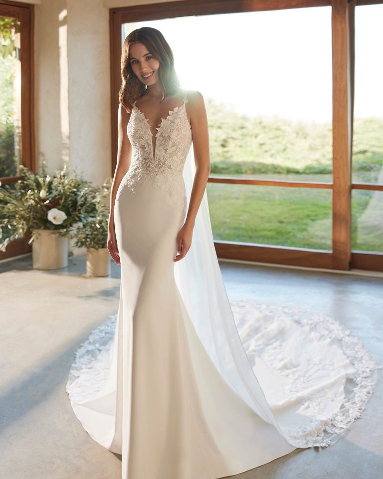Long bridal dress, two-piece and mermaid cut. Crafted in crepe and lace with an illusion neckline, straps, and open back with cape. ALMA_NOVIA.