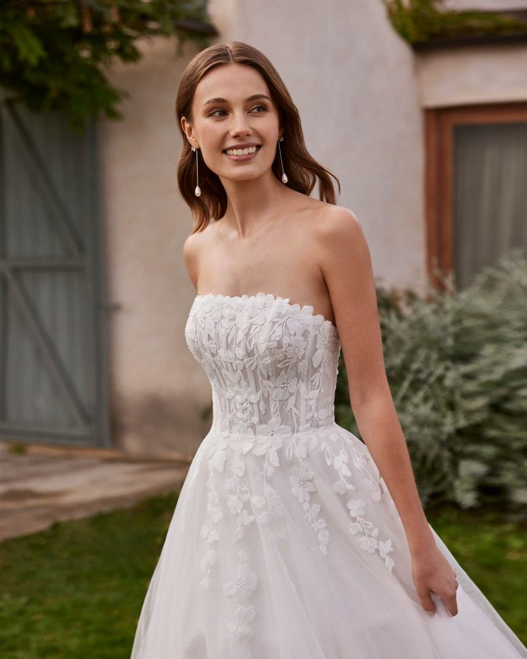 Long bridal dress, two-piece and A-line. Crafted in tulle and lace with a strapless neckline and lace jacket. ALMA_NOVIA.