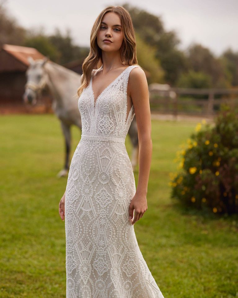 Long bridal dress with a mermaid cut. Crafted in guipure with a V-neckline, straps, and open back. ALMA_NOVIA.