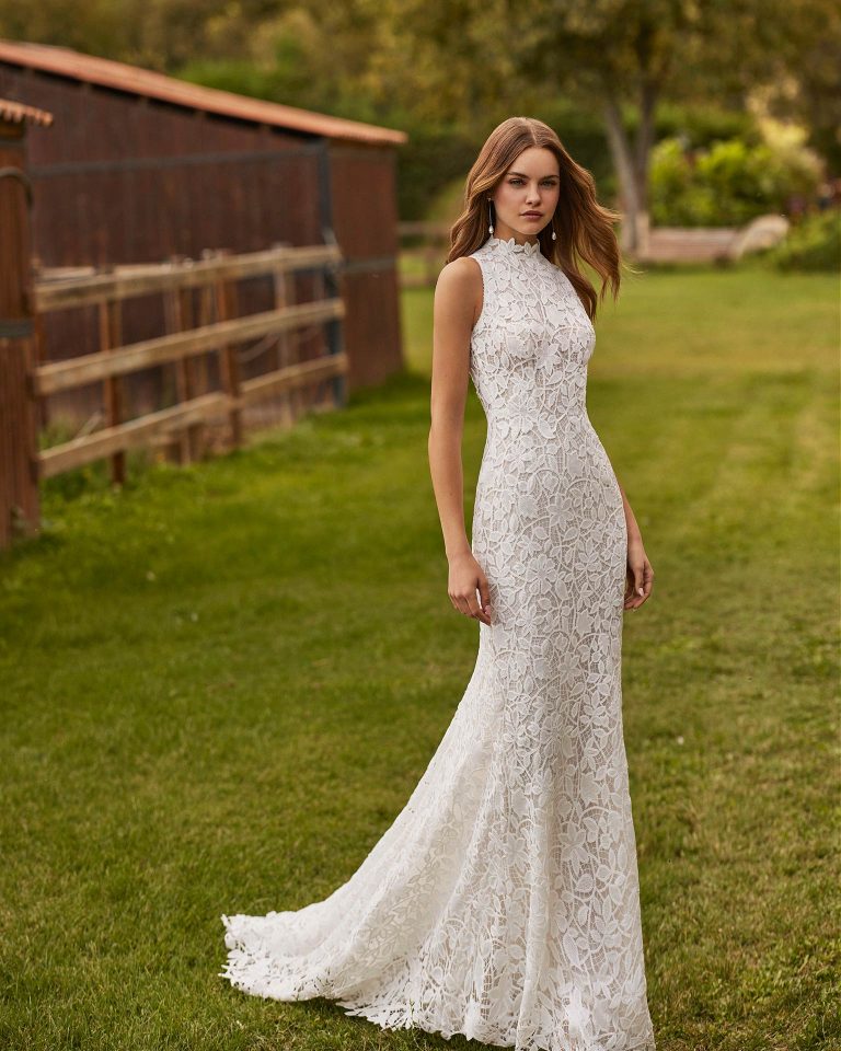 Long bridal dress with a mermaid cut. Crafted in guipure with a halter neckline and back with a round opening. ALMA_NOVIA.