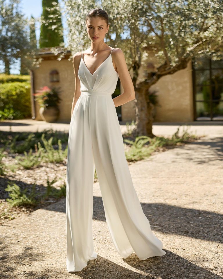 Vestido pantalón de novia de dos piezas en crespón con escote pico, tirantes, espalda en V y cuerpo drapeado. Incluye abrigo en georgette. ALMA_NOVIA.