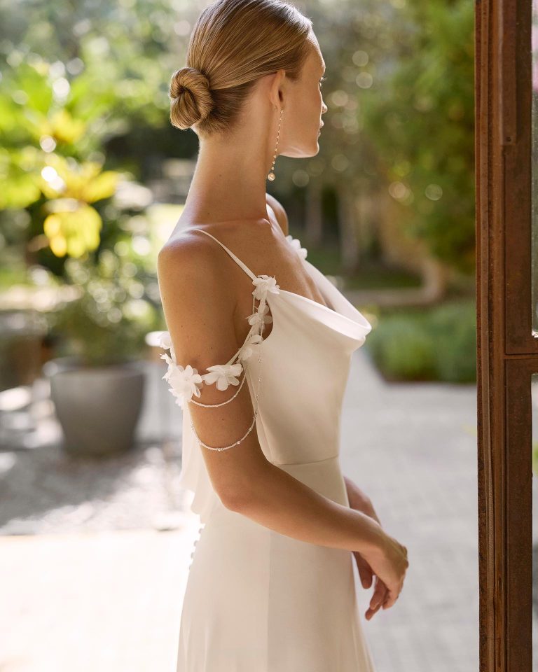 Vestido de novia en crespon, de silueta recta con escote drapeado, tirantes con adornos florales. Espalda con cremallera. ALMA_NOVIA.
