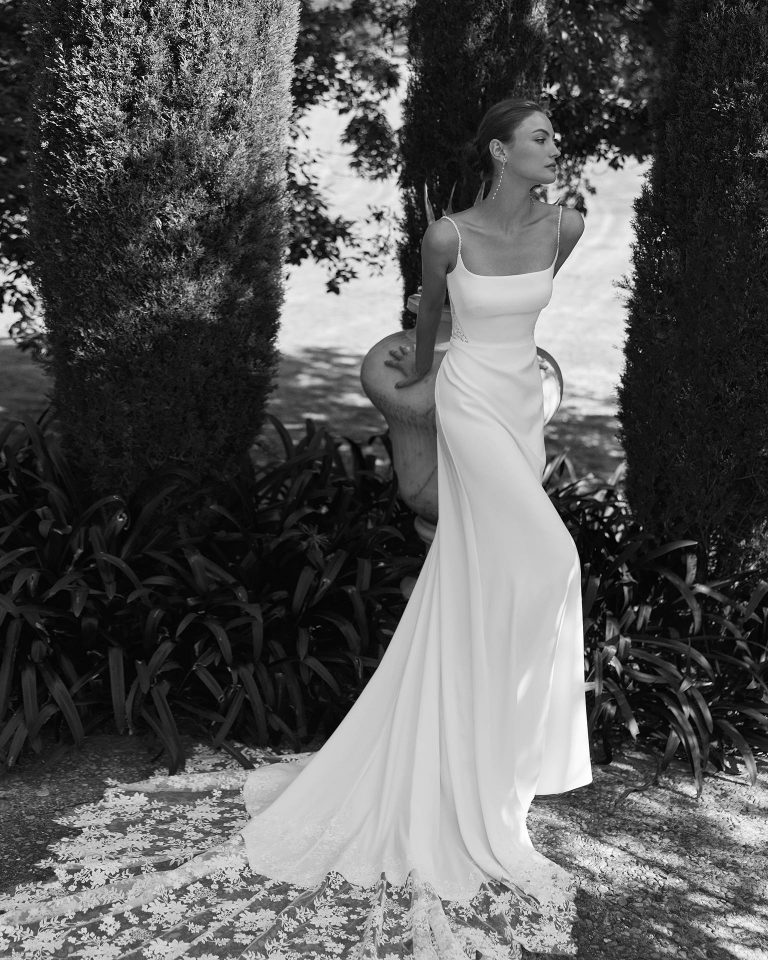 Vestido de novia de silueta recta en georgette con escote y espalda cuadrados, tirantes con pedrería, falda con apliques y cierre de cremallera. ALMA_NOVIA.