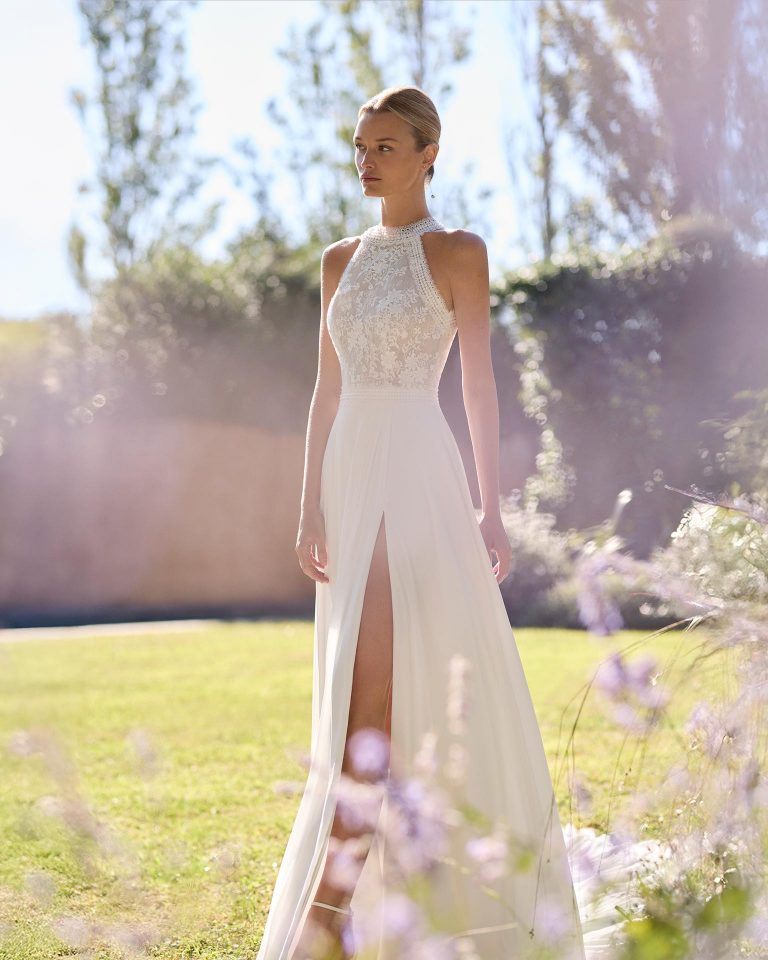 Vestido de novia de dos piezas con cuerpo de encaje y pedrería, escote halter, espalda con abertura. Falda línea A de georgette con abertura delantera y cola. ALMA_NOVIA.