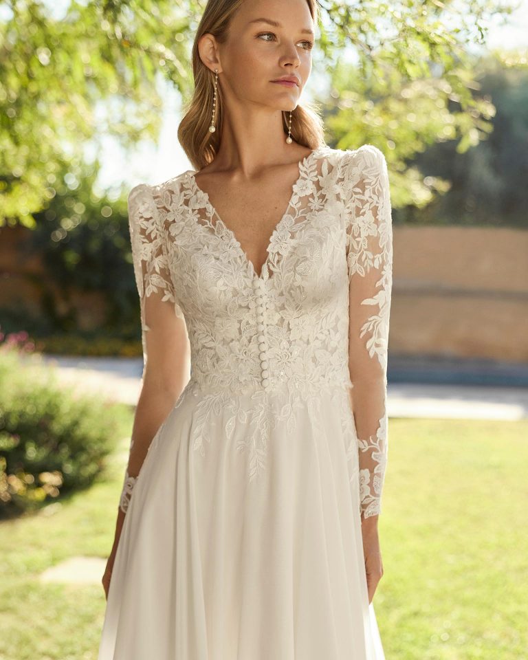 Vestido de novia de dos piezas con cuerpo de encaje y pedrería, escote pico, espalda en V, tirantes y falda línea A de georgette. Incluye chaqueta de encaje. ALMA_NOVIA.