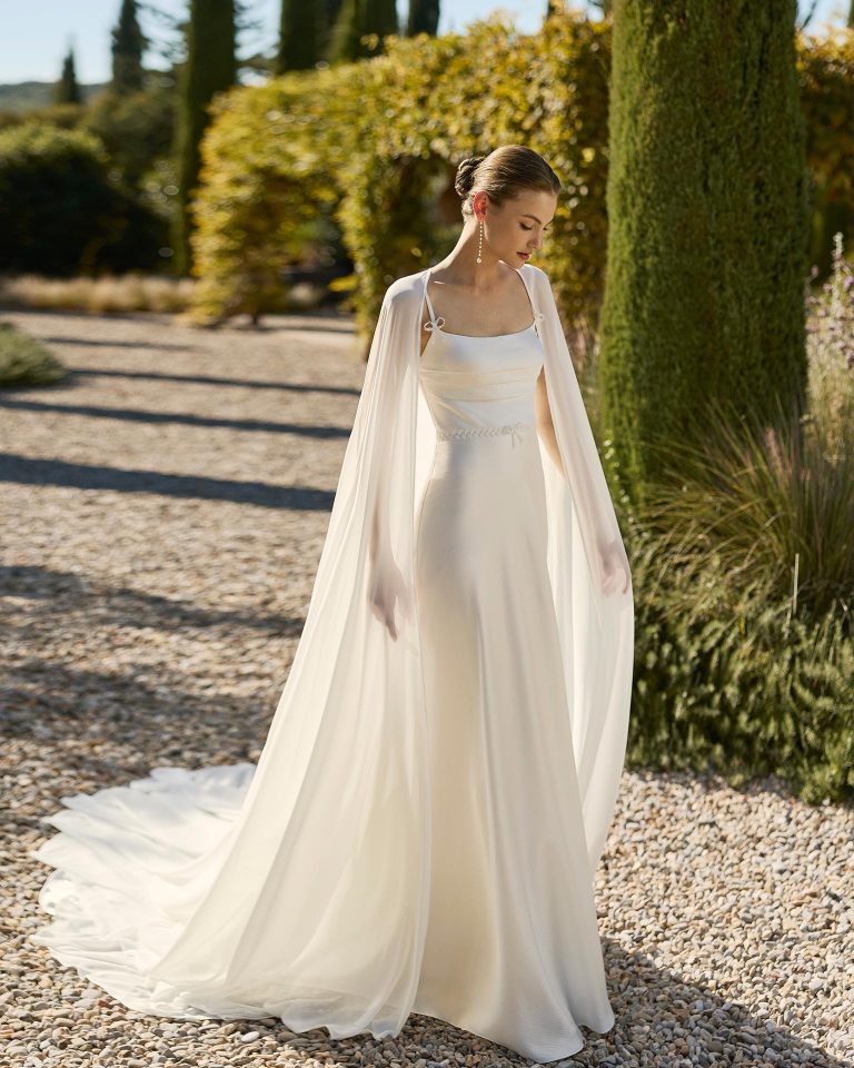 Vestido de novia de dos piezas con silueta en línea A, escote cuadrado y tirantes. Confeccionado en satén texturizado con pedrería en el corpiño. Incluye capa de georgette. ALMA_NOVIA.