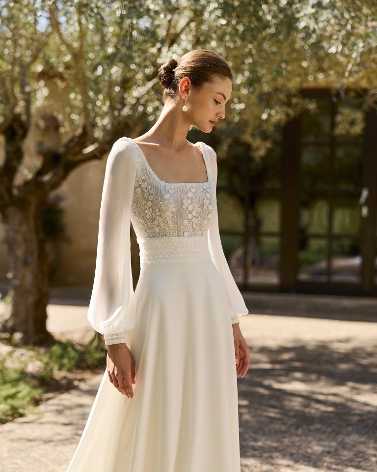 Vestido de novia silueta línea A con escote cuadrado, manga abullonada, cuerpo de encaje con fajín y falda de crepé elástico. Espalda cuadrada abotonada. ALMA_NOVIA.
