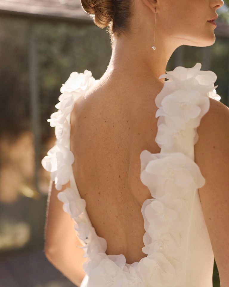 Vestido de novia de dos piezas en crepé elástico con silueta línea A, escote redondo, espalda abierta, adornos florales en el cuerpo y cola lisa. ALMA_NOVIA.