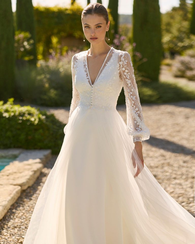 Vestido de novia de dos piezas en crepé elástico con silueta línea A, escote pico y espalda en V con cierre de cremallera. Incluye abrigo de encaje. ALMA_NOVIA.