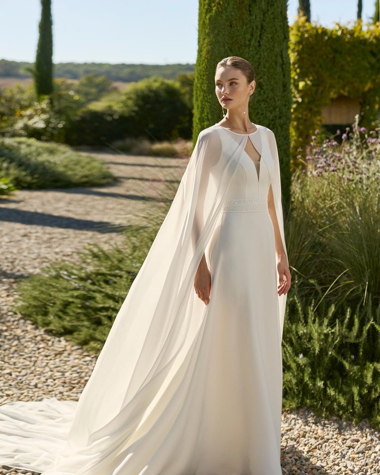 Vestido de novia dos piezas silueta línea A con escote profundo, manga poeta larga y espalda con abertura. Incluye capa de georgette. ALMA_NOVIA.