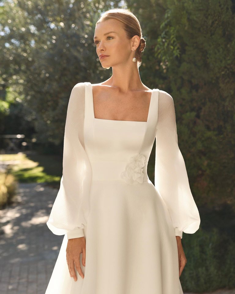 Vestido de novia línea A en organza Lira con escote cuadrado, espalda escotada, manga poeta larga extraíble, adornos florales y cremallera. ALMA_NOVIA.